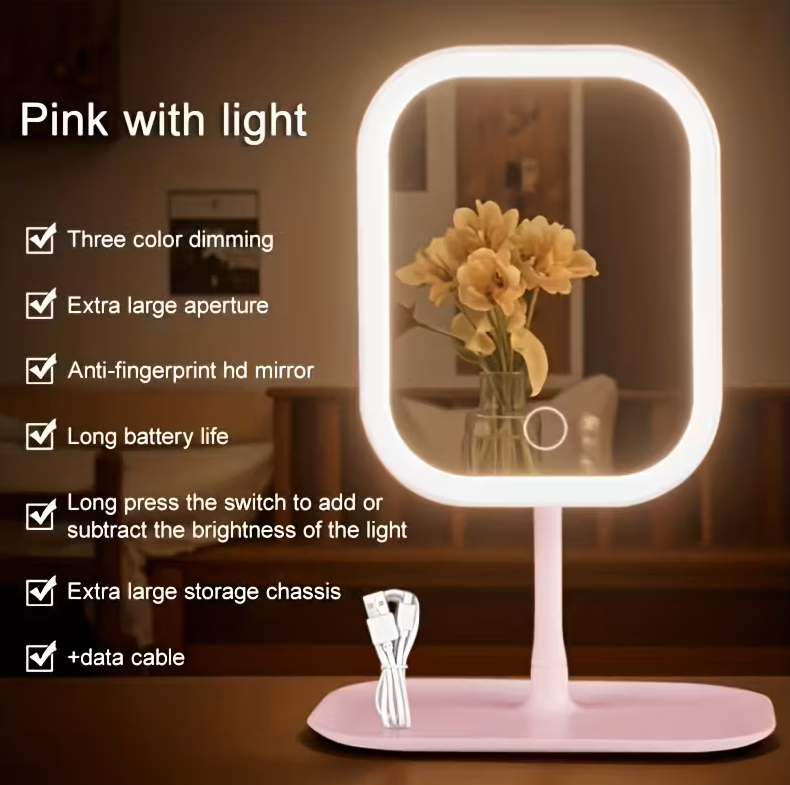 Pink LED makeup mirror with warm lighting displayed in a lifestyle setting, with feature callouts including three colour dimming, anti-fingerprint HD mirror, long battery life, and extra large storage chassis