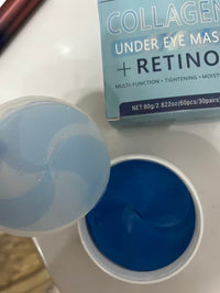 Open jar of blue under-eye patches with its clear inner cover and product box beside it.